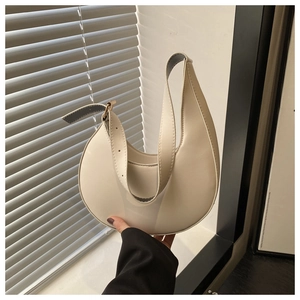 Detail of off-white crescent underarm bag with adjustable strap and golden metal eyelets