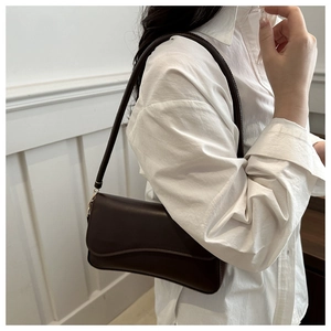 Detail view of dark coffee matte leather shoulder bag with a curved flap design