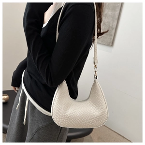 Detail of white woven hobo bag with moon shape and golden metallic hardware