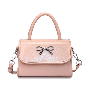Pink crossbody bag with a silver metal bow and polished embossed leather finish