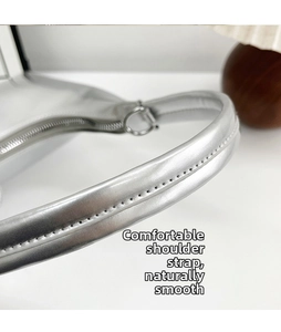 Detail of silver metallic shoulder strap with smooth stitching and round metal buckle
