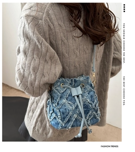 Dettaglio borsa a secchiello in denim con trama trapuntata e coulisse sulla modella