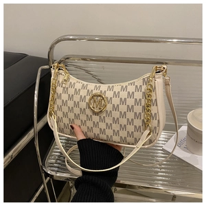 Detail of cream crescent bag featuring M letter jacquard pattern and gold metal hardware