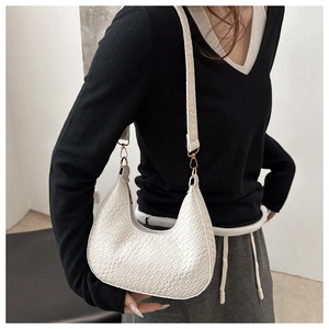 Detail of white woven hobo bag with gold hardware and wide shoulder strap style