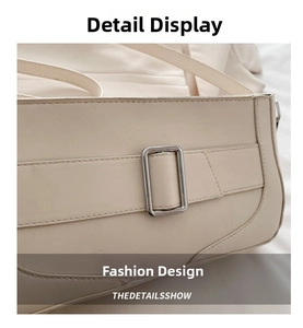 Detail of silver metal buckle and neat stitching on creamy beige leather shoulder bag