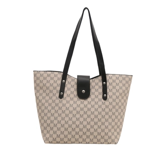 Classic beige tote bag with M-pattern print and black leather handles on white background