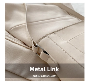 Detailed close-up of the beige shoulder bag showing reinforced stitching and silver metal link