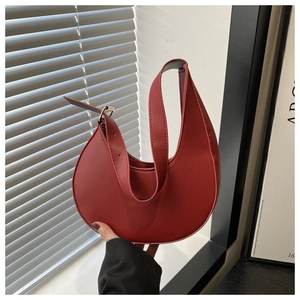Close-up of red crescent bag made of matte faux leather with adjustable strap