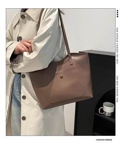 Brown leather tote bag featuring a front pocket with metal snap button for commuting