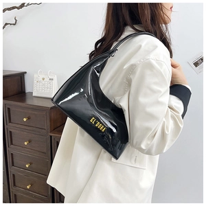 Close-up of glossy black patent leather shoulder bag with golden logo lettering