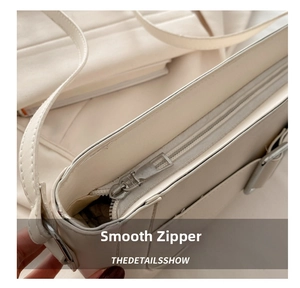 Detailed macro view of a cream-white leather handbag showing smooth metal zipper and stitching
