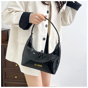 Close-up of black glossy hobo bag with yellow lettering and metallic zipper detail