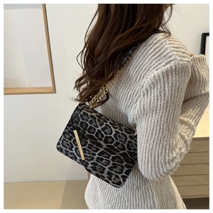 Detail of leopard print shoulder bag featuring gold chain strap and metal buckle closure