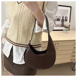 Chic brown woven crescent hobo bag worn by a model in a cozy minimalist home setting