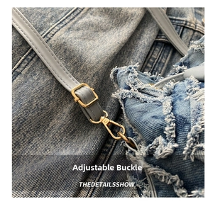 Macro della tracolla regolabile in pelle con fibbia dorata su borsa di jeans