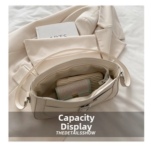 Interior view of minimalist cream shoulder bag showing main compartment and zipper pocket