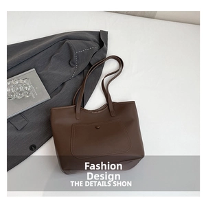 Detail of minimalist dark brown tote bag featuring outer curved pocket and magnetic snap