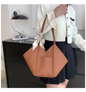 Detail of a brown leather tote bag with geometric design and decorative floral scarf