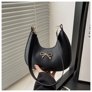 Detail der schwarzen PU Hobo-Tasche mit goldener Schleife im natürlichen Licht