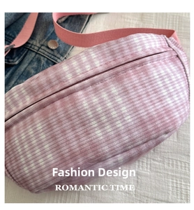Detail of a pink and purple plaid corduroy chest bag with a woven shoulder strap