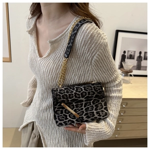 Détail d'un sac bandoulière léopard avec chaîne dorée porté par un mannequin en intérieur