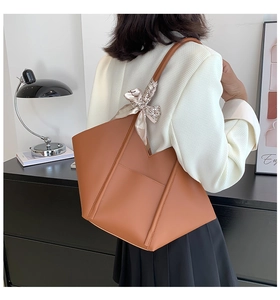 Detail of brown leather tote bag with stylish monochrome patterned silk scarf on handle