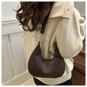 Detail of dark brown woven texture on a hobo shoulder bag with golden metal hardware