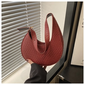 Detail of reddish-brown crescent bag with woven texture and gold metal buckle hardware