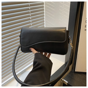 Close-up of matte black underarm bag with unique wave-edge flap and premium leather texture