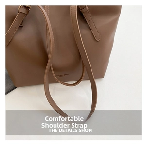 Detail of adjustable metal buckle and thin shoulder strap on brown leather tote bag