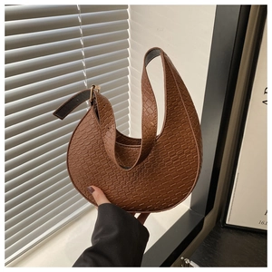 Macro detail of brown crocodile embossed moon bag with golden buckle on adjustable strap