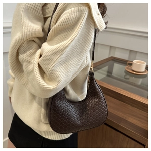 Detail of dark brown woven texture hobo bag with elegant gold metal clasp on shoulder strap