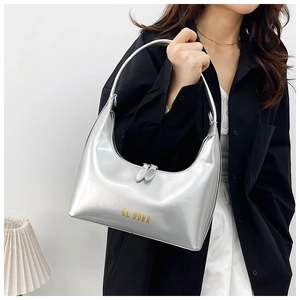 Close-up of a silver mirror finish hobo bag featuring a gold brand logo on a shoulder strap