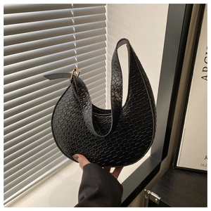 Detail of black crocodile texture on a crescent moon bag with a gold buckle and handle