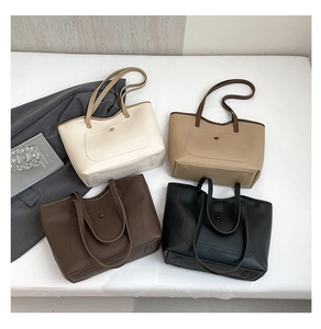 Flat lay of four large faux leather tote bags in white, khaki, dark coffee, and black tones
