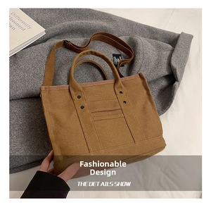 Detail of khaki canvas tote bag with adjustable shoulder strap and rivet accents