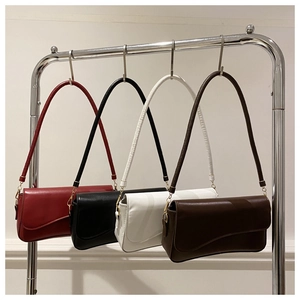 Minimalist flap bags in burgundy, black, cream, and brown on a sleek metal display stand