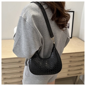 Detail of black woven texture hobo bag on model with elegant gold metal buckles