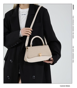 Detail of light beige woven texture crossbody bag with gold hardware on a model