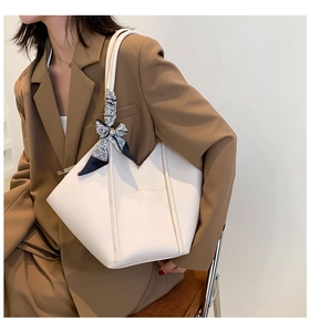 Detail of white geometric tote bag with patterned silk scarf on a brown blazer outfit