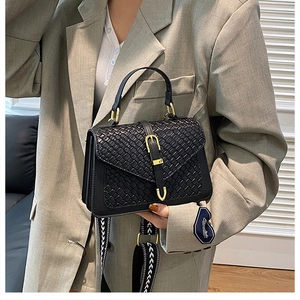 Detail of black woven leather handbag with gold buckle and geometric pattern strap