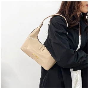 Detail of cream patent leather baguette bag with gold lettering and sleek double zippers