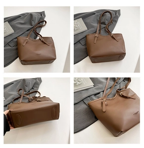 Detail of brown tote bag showing adjustable gold buckle and embossed brand lettering