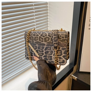 Détail d'un sac à bandoulière imprimé léopard avec chaîne dorée tenu par une personne