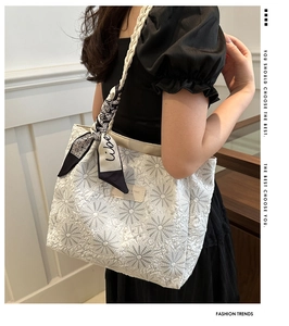 Detail of white tote bag with daisy embroidery and elegant silk scarf accessory