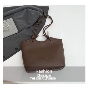 Overhead view of a dark brown matte leather tote bag with knotted cord straps and fashion label