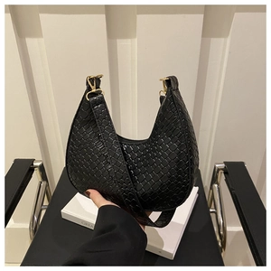 Detail of black crescent hobo bag with woven texture and gold metal buckle accents