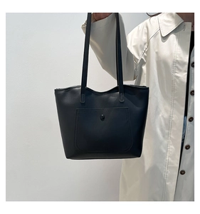 Detail view of black tote bag featuring a stitched front pocket and slim double shoulder straps