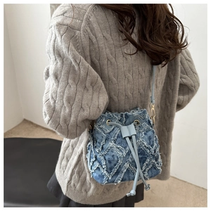 Dettaglio borsa a secchiello in denim blu con coulisse, trapuntatura a rombi e oro