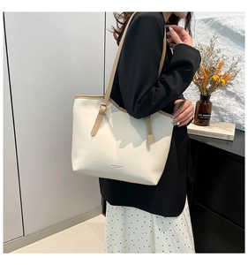 Detail of cream leather tote bag featuring a brown adjustable strap and fashion logo